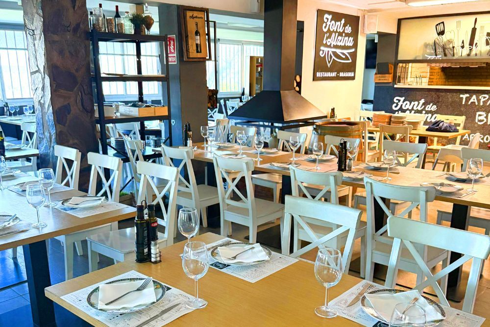 Salón comedor principal con luz natural y montaje de mesas en Restaurant Font de l'Alzina
